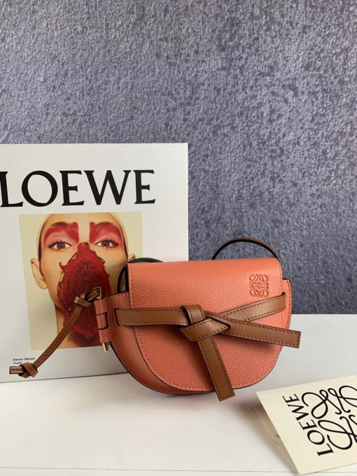 LOEWE Gate Mini Grained-Leather Cross-Body Bag. Original Quality Bag. Authentic Style. Genuine Calf Leather. Metal Hardware. Authentic Packaging. Original Quality Dust Bag. Loewe brings signature finesse to the micro-mini bag trend with this tiny red iteration of its coveted Gate style. The bag takes inspiration from countryside gate latch fastenings to create this grained-leather Gate cross-body bag. It's crafted to a half-moon shape with a long shoulder strap that is finished with black lacquered edges, then opens to reveal a suede interior with a single slip pocket. | CRIS&COCO Store | High Quality Designer Handbag