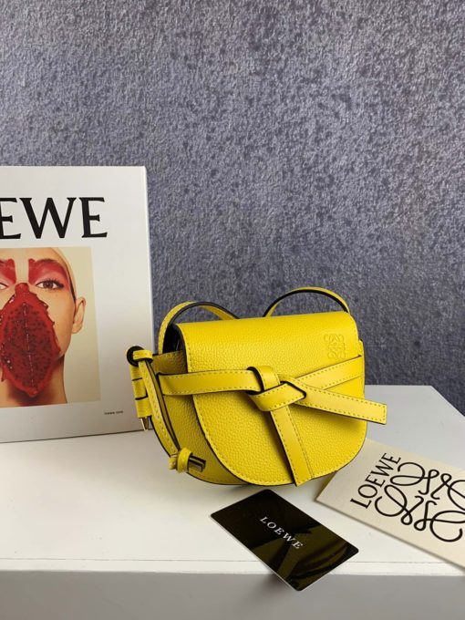 LOEWE Gate Mini Grained-Leather Cross-Body Bag. Original Quality Bag. Authentic Style. Genuine Calf Leather. Metal Hardware. Authentic Packaging. Original Quality Dust Bag. Loewe brings signature finesse to the micro-mini bag trend with this tiny red iteration of its coveted Gate style. The bag takes inspiration from countryside gate latch fastenings to create this grained-leather Gate cross-body bag. It's crafted to a half-moon shape with a long shoulder strap that is finished with black lacquered edges, then opens to reveal a suede interior with a single slip pocket. | CRIS&COCO Store | High Quality Designer Handbag