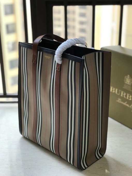 BURBERRY Icon Stripe E-Canvas Portrait Tote Bag. Authentic Quality Bag with literature, gift box, dust bag and authenticity card. A tote bag in environmentally conscious e-canvas, primarily made using renewable resources that require less water and generate less CO2 than conventional coated canvases. The style is printed with our Icon stripe and finished with smooth leather handles. | CRIS&COCO Authentic Quality Designer Bags and Luxury Accessories