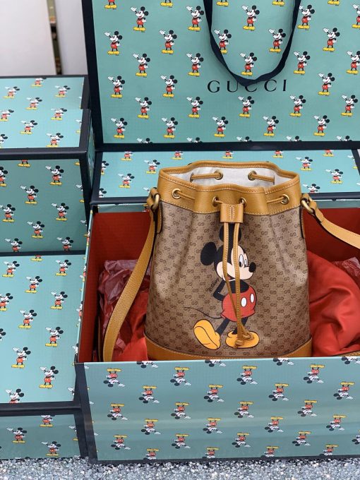 DISNEY x GUCCI Bucket Bag. Authentic Quality Bag including gift box, literature, dust bag, authenticity card. DISNEY and GUCCI come together for an exclusive collection. Mickey Mouse’s playful image defines this GG canvas bucket bag, trimmed with light brown leather details that convey a vintage look and feel. DISNEY’s legendary character appears throughout GUCCI’s ready-to-wear and accessories for the Cruise 2020 collection, displayed as colorful prints, embroidered patches or jacquard motifs.| Cris and Coco. Authentic Quality Designer Bags and Luxury Accessories