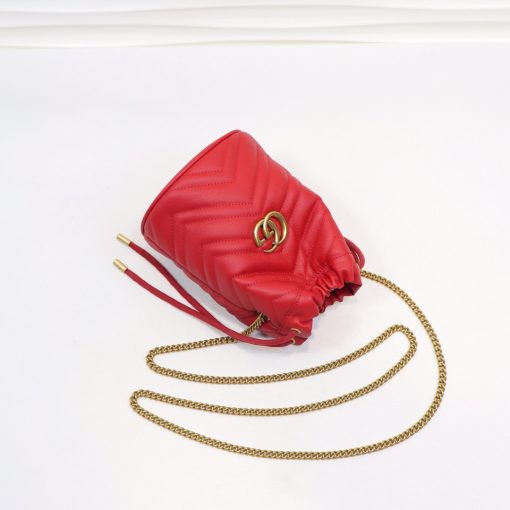 GUCCI GG Marmont Mini Bucket Bag. Original Quality Bag including gift box, literature, dust bag, authenticity card. The world of GG Marmont expands with the introduction of a mini bucket bag shape crafted from Matelassé leather in vibrant tones. Inspired by an archival design from the '70s, a hallmark era of the House, the Double G decorates the front of this accessory. Featuring a chain strap and drawstring closure the versatile shape can be worn as shoulder and as a crossbody bag. | Cris and Coco. High Quality Bags and Luxury Accessories