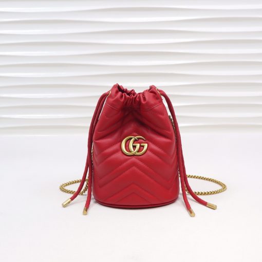 GUCCI GG Marmont Mini Bucket Bag. Original Quality Bag including gift box, literature, dust bag, authenticity card. The world of GG Marmont expands with the introduction of a mini bucket bag shape crafted from Matelassé leather in vibrant tones. Inspired by an archival design from the '70s, a hallmark era of the House, the Double G decorates the front of this accessory. Featuring a chain strap and drawstring closure the versatile shape can be worn as shoulder and as a crossbody bag. | Cris and Coco. High Quality Bags and Luxury Accessories