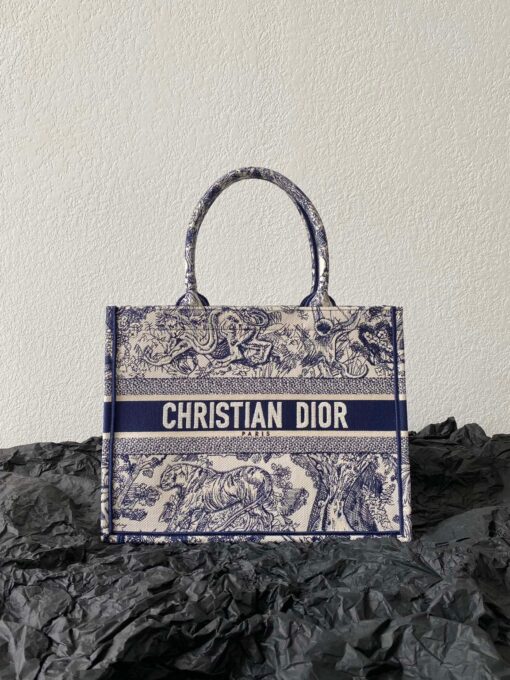 DIOR Book Tote. Original Quality Bag including gift box, care book, dust bag, authenticity card. This Book Tote is an original style introduced by Creative Director Maria Grazia Chiuri. This has become a staple of the Dior aesthetic. Ideally designed to carry all your daily essentials, the small shape is fully embroidered and the 'Christian Dior' signature on the front. This carryall is a perfect example of the Dior savoir-faire and also may be coordinated with a pouch or other small leather goods for a complete look. | CRIS&COCO Authentic Quality Designer Bags and Luxury Accessories