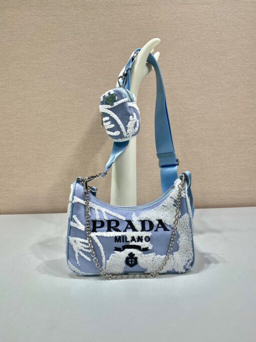 PRADA Re-Edition 2006 Embroidered Drill Shoulder Bag. Original Quality Bag including gift box, care book, dust bag, authenticity card. A new interpretation of an iconic Prada style, this Re-Edition 2005 bag features luxurious embroidery that creates a three-dimensional effect. Completed with a coordinated pouch that attaches to the shoulder strap, the bag can be worn in different ways thanks to the adjustable woven tape shoulder strap and chain handle. | CRIS&COCO Authentic Quality Designer Bags and Luxury Accessories