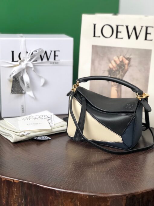 LOEWE Mini Puzzle Bag. Original Quality Bag including gift box, care book, dust bag, authenticity card. The Puzzle bag is the debut bag for LOEWE by Creative Director Jonathan Anderson. A cuboid shape and precise cutting technique create Puzzle’s distinctive geometric lines. This mini version is crafted in contrasting calfskins. | CRIS AND COCO Authentic Quality Luxury Accessories