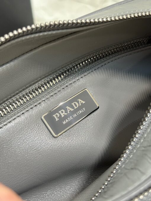 PRADA Nappa Antique Leather Shoulder Bag. High-End Quality Bag including gift box, care book, dust bag, authenticity card. This bag with compact allure is made of nappa leather with a natural, glossy finish. The hand-made wrinkled effect contrasts with the constructed and rigid concept, reinterpreting an everyday object to be worn without constraints. Presented in the Spring Summer 2023 show, the style is accented with a finely embroidered shoulder strap with a sporty mood. | CRIS AND COCO Authentic Quality Luxury Accessories