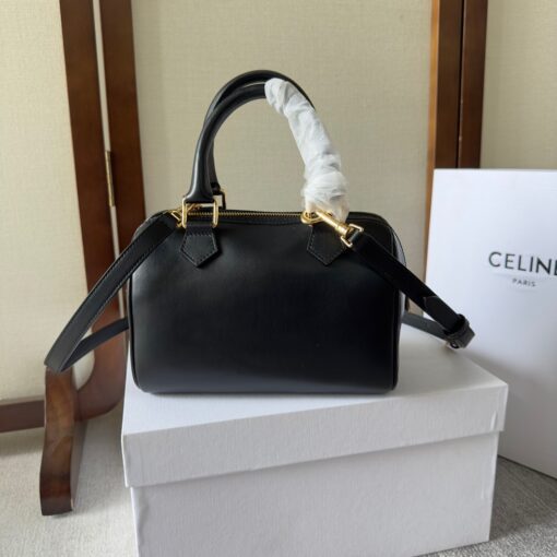 CELINE Small Boston Cuir Triomphe. Style meets sophistication with this timeless Celine Bag. The Celine Small Boston Cuir Triomphe is a classic accessory that is perfect for both day and night. It is made out of smooth calfskin leather with a stitched monogram pattern that creates an elegant, modern look. The bag features a removable and adjustable shoulder strap, a top handle for carrying, and a zipped closure. It also has a main spacious compartment, and one inner flat pocket. It has a small and compact size, perfect for days when you don't want to carry too much. The timeless design will never go out of style, and you'll be sure to feel confident and stylish with this bag on your arm. | CRIS AND COCO Authentic Quality Luxury Accessories