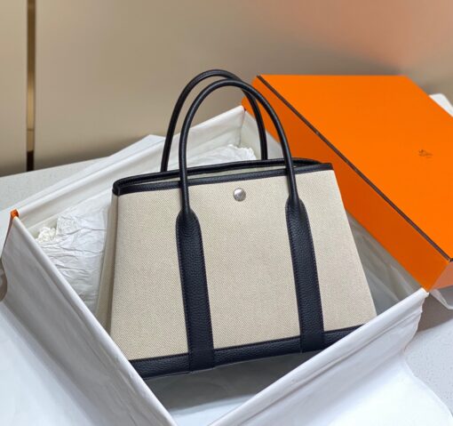 HERMÈS Garden Party: Style for Every Occasion. This Garden Party tote is the perfect blend of style and practicality. This chic and sporty bag is designed for every occasion, whether spending the day amongst the hustle and bustle of the city or enjoying a peaceful weekend in the countryside. Crafted with both leather and canvas, it's the perfect choice for whatever your destination. Not only is it spacious enough to hold your everyday essentials, but it also features Clou de Selle snap closures on the sides for added convenience. This snap that allows the bag to be just the right amount of malleable; to expand and create extra interior space to accommodate larger, or more items at once. Wherever your adventures take you, this exclusive HERMÈS tote will accompany you every step of the way. | CRIS&COCO Authentic Quality Designer Bags and Luxury Accessories