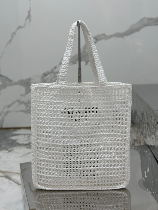 PRADA Crochet Tote Bag. Elevate your style with Prada's signature tote bag. This tote bag is the perfect addition to any summer wardrobe! Adorned with Prada's iconic triangle logo and embroidered lettering, its soft, deconstructed design is made with a light and natural raffia-effect yarn. It's sure to add an elevated touch to your ensemble. | CRIS&COCO Authentic Quality Designer Bags and Luxury Accessories