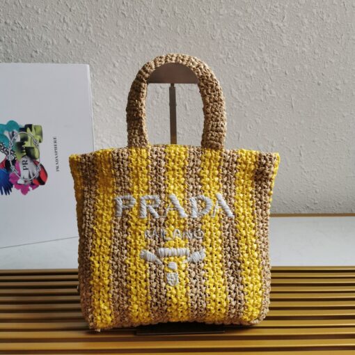 PRADA Small Crochet Tote Bag. Elevate Your Look with an Exquisite Tote Bag! This exquisite tote bag has a deconstructed design made of a light, natural material with a summery mood, raffia-effect yarn. Embroidered lettering logo decorates the front, and the emblematic triangle in enameled metal is the perfect finishing touch to the side. | CRIS&COCO Authentic Quality Designer Bags and Luxury Accessories