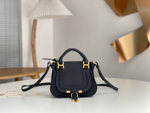 CHLOÉ Marcie Mini Double Carry Bag: Elegance in Miniature. Introducing a charming, petite rendition of the iconic Marcie handbag, this mini double carry bag exudes elegance with its meticulous craftsmanship in grained calfskin. Its clean, sleek lines and gracefully contoured design elevate the relaxed, slouchy silhouette, while the hand-wrapped leather handles impart an artisanal touch. The addition of metallic buckles bestows a polished and refined finish to this exquisite creation. Equipped with both double handles and a long, detachable shoulder strap, this mini bag epitomizes versatility, making it a must-have accessory for any occasion.