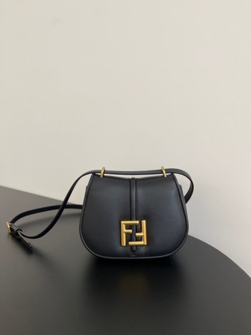 FENDI C’mon Mini. Embrace Elegance: Stefano Pilati's Curvaceous Creation. A petite satchel bag, graced with graceful, feminine curves, represents a masterpiece from the illustrious collection envisioned by the renowned Stefano Pilati. Fashioned from sumptuously smooth leather, this exquisite piece is adorned with meticulously embossed accents and edges, culminating in a striking FF logo proudly showcased on its elegant flap.