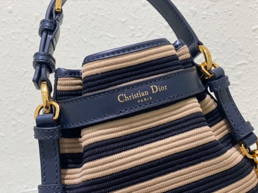 DIOR Small C'est Bag: Timeless Elegance, Effortless Style. Introducing the C'est Dior bag, a timeless and elegant creation for Fall 2023. Crafted in natural and denim blue raffia, it beautifully features the classic Marinière motif from ready-to-wear. Securing your essentials with a sophisticated CD Lock closure adorned with a twisting letter D, this bucket bag combines style with practicality. With a top handle and an adjustable, removable chain strap featuring a leather insert, this small-sized bag offers versatile carrying options—be it hand-held or comfortably draped over the shoulder.
