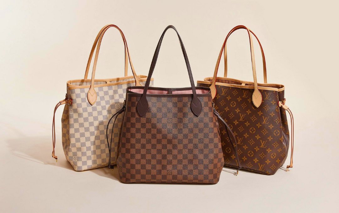 Luxury Louis Vuitton Neverfull tote bag on marble countertop with accessories.