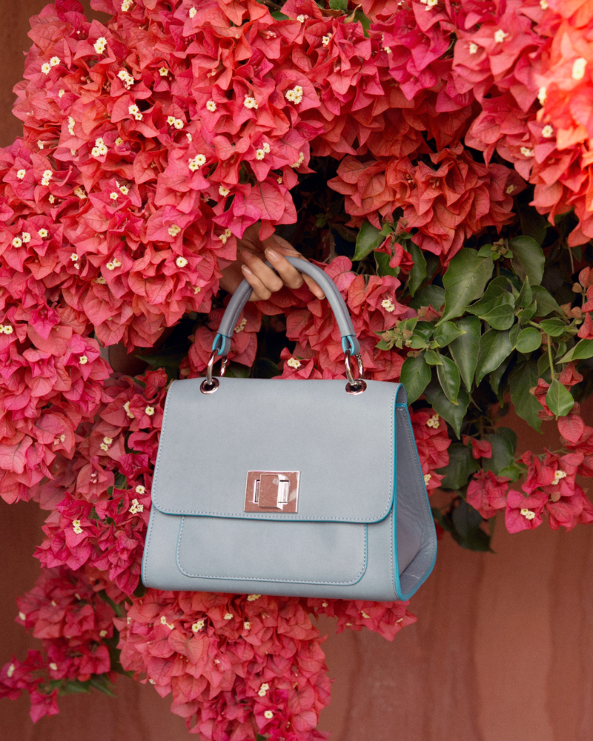 Elegance in Bloom: A Timeless Flap Bag with a Floral TouA classic flap bag set against a colorful floral background, showcasing its elegant design amidst vibrant blooms.ch