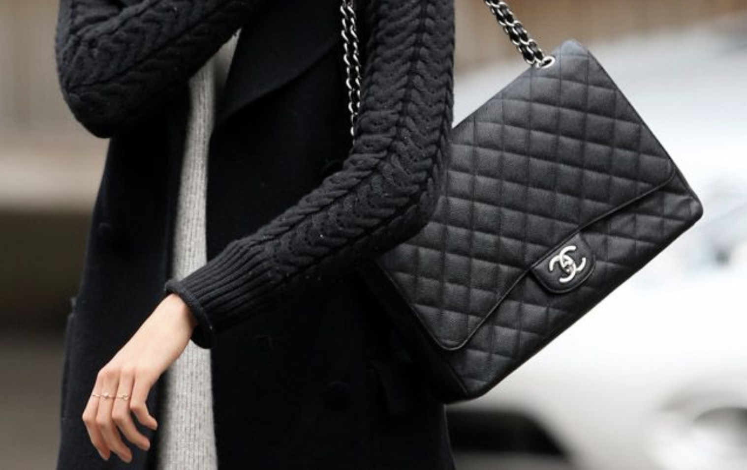 A woman wearing a CHANEL Flap-inspired bag, strolling down a city street.