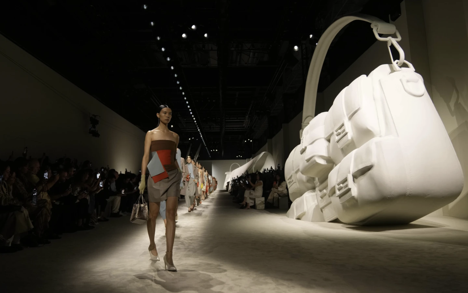 Runway model carrying a designer handbag as the focal point of the show.