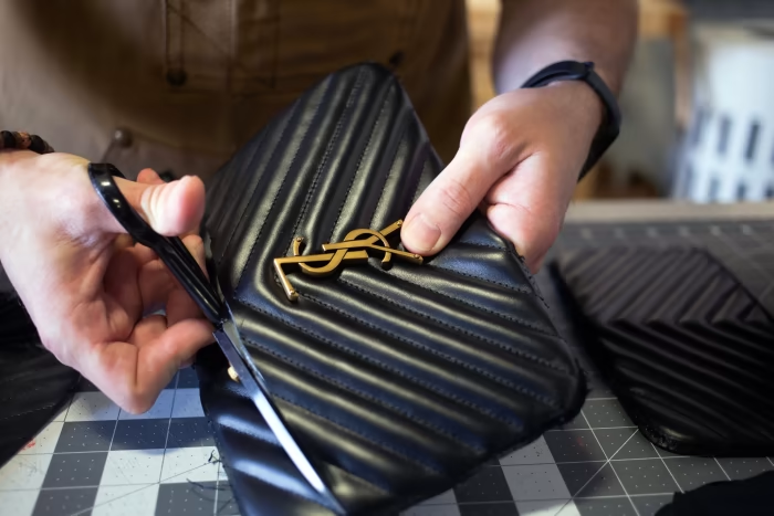 A craftsman working on a replica luxury bag in a factory.