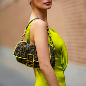 A close-up of a stylish woman holding a high-quality designer-inspired bag, standing against a luxury boutique backdrop.