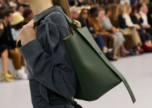 A stylish woman holding a designer-inspired handbag, exuding confidence and elegance.