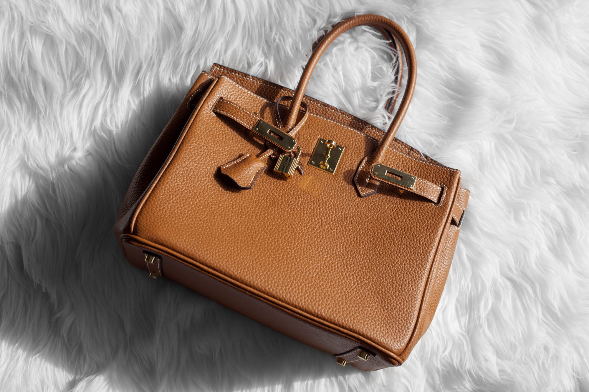 A tan HERMÈS Birkin bag displayed on a luxury boutique counter.