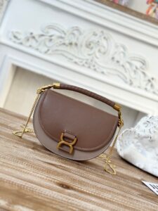 Marcie Chain Flap Bag. Authentic quality luxury bag crafted in genuine leather comes with authenticity card, dust bag and gift bag. Elevating Iconic Elegance: Marcie Line Redefined. Experience a fresh take on *loé's iconic Marcie line with this exquisite chain flap bag, meticulously crafted from a captivating blend of nappa lambskin, grained calfskin, and sumptuous suede. The line's signature hardware undergoes a graceful transformation, now adorned with *loé's engraved jewelry hallmark, adorning the flap with sophistication. An intricately hand-braided top handle pays homage to another hallmark Marcie feature, while a gracefully extended chain strap adds a refined touch. Whether you choose to drape it over your shoulder or wear it cross-body during the day, or opt to detach the strap and carry it by hand for a sophisticated evening ensemble, this flap bag is a versatile masterpiece. *loé's Marcie bag line effortlessly melds a feminine aesthetic with the free-spirited vibe of the '70s. An equestrian-inspired allure takes center stage, elevated by the allure of gleaming gold-toned hardware, resulting in a distinctly feminine yet timelessly chic look. - CRIS&COCO Marcie Chain Flap Bag. Authentic quality luxury bag crafted in genuine leather comes with authenticity card, dust bag and gift bag. Elevating Iconic Elegance: Marcie Line Redefined. Experience a fresh take on *loé's iconic Marcie line with this exquisite chain flap bag, meticulously crafted from a captivating blend of nappa lambskin, grained calfskin, and sumptuous suede. The line's signature hardware undergoes a graceful transformation, now adorned with *loé's engraved jewelry hallmark, adorning the flap with sophistication. An intricately hand-braided top handle pays homage to another hallmark Marcie feature, while a gracefully extended chain strap adds a refined touch. Whether you choose to drape it over your shoulder or wear it cross-body during the day, or opt to detach the strap and carry it by hand for a sophisticated evening ensemble, this flap bag is a versatile masterpiece. *loé's Marcie bag line effortlessly melds a feminine aesthetic with the free-spirited vibe of the '70s. An equestrian-inspired allure takes center stage, elevated by the allure of gleaming gold-toned hardware, resulting in a distinctly feminine yet timelessly chic look.