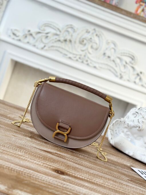 Marcie Chain Flap Bag. Authentic quality luxury bag crafted in genuine leather comes with authenticity card, dust bag and gift bag. Elevating Iconic Elegance: Marcie Line Redefined. Experience a fresh take on *loé's iconic Marcie line with this exquisite chain flap bag, meticulously crafted from a captivating blend of nappa lambskin, grained calfskin, and sumptuous suede. The line's signature hardware undergoes a graceful transformation, now adorned with *loé's engraved jewelry hallmark, adorning the flap with sophistication. An intricately hand-braided top handle pays homage to another hallmark Marcie feature, while a gracefully extended chain strap adds a refined touch. Whether you choose to drape it over your shoulder or wear it cross-body during the day, or opt to detach the strap and carry it by hand for a sophisticated evening ensemble, this flap bag is a versatile masterpiece. *loé's Marcie bag line effortlessly melds a feminine aesthetic with the free-spirited vibe of the '70s. An equestrian-inspired allure takes center stage, elevated by the allure of gleaming gold-toned hardware, resulting in a distinctly feminine yet timelessly chic look.