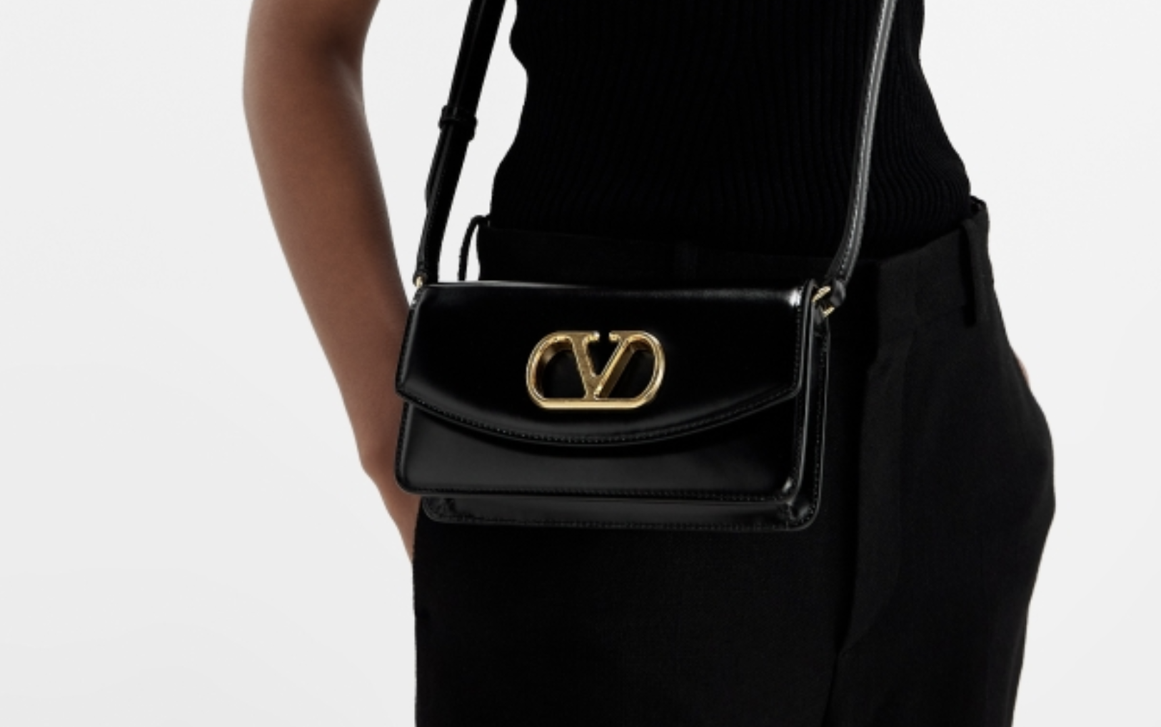 VALENTINO leather clutch replica with bold gold V logo resting on mirrored vanity VALENTINO leather clutch replica with bold gold V logo resting on mirrored vanity