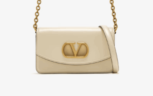 Close-up of gold V logo on VALENTINO replica clutch in studio lighting