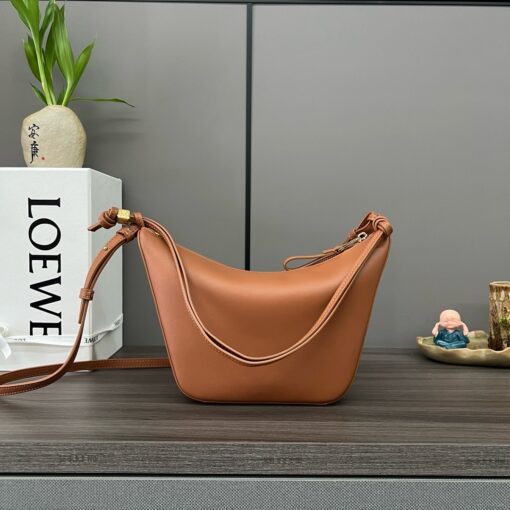 Mini Hammock Hobo. Authentic quality luxury bag crafted in genuine leather comes with authenticity card, dust bag and gift bag. Effortless Form, Everyday Function.  The Mini Hammock Hobo is a contemporary reimagining of Loewe’s iconic Hammock bag. This streamlined variation offers a sleek, sculptural silhouette designed as a versatile sling bag for modern living. Expertly crafted in classic calfskin, it features soft, supple leather and a compact form that adapts effortlessly to your day. The unique design allows for multiple carry options—wear it crossbody, over the shoulder, or by hand. Elegant yet functional, this mini hobo is perfect for essentials, making it an ideal choice for both daily wear and minimalist style statements.
