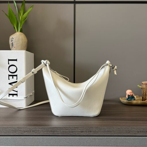 Mini Hammock Hobo. Authentic quality luxury bag crafted in genuine leather comes with authenticity card, dust bag and gift bag. Effortless Form, Everyday Function.  The Mini Hammock Hobo is a contemporary reimagining of Loewe’s iconic Hammock bag. This streamlined variation offers a sleek, sculptural silhouette designed as a versatile sling bag for modern living. Expertly crafted in classic calfskin, it features soft, supple leather and a compact form that adapts effortlessly to your day. The unique design allows for multiple carry options—wear it crossbody, over the shoulder, or by hand. Elegant yet functional, this mini hobo is perfect for essentials, making it an ideal choice for both daily wear and minimalist style statements.