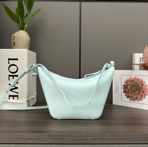 Mini Hammock Hobo. Authentic quality luxury bag crafted in genuine leather comes with authenticity card, dust bag and gift bag. Effortless Form, Everyday Function.  The Mini Hammock Hobo is a contemporary reimagining of Loewe’s iconic Hammock bag. This streamlined variation offers a sleek, sculptural silhouette designed as a versatile sling bag for modern living. Expertly crafted in classic calfskin, it features soft, supple leather and a compact form that adapts effortlessly to your day. The unique design allows for multiple carry options—wear it crossbody, over the shoulder, or by hand. Elegant yet functional, this mini hobo is perfect for essentials, making it an ideal choice for both daily wear and minimalist style statements.