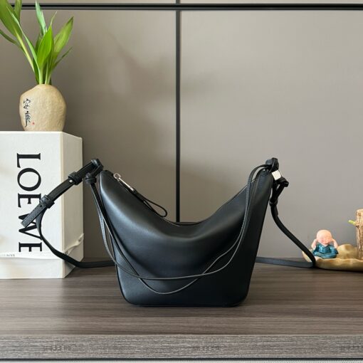 Mini Hammock Hobo. Authentic quality luxury bag crafted in genuine leather comes with authenticity card, dust bag and gift bag. Effortless Form, Everyday Function.  The Mini Hammock Hobo is a contemporary reimagining of Loewe’s iconic Hammock bag. This streamlined variation offers a sleek, sculptural silhouette designed as a versatile sling bag for modern living. Expertly crafted in classic calfskin, it features soft, supple leather and a compact form that adapts effortlessly to your day. The unique design allows for multiple carry options—wear it crossbody, over the shoulder, or by hand. Elegant yet functional, this mini hobo is perfect for essentials, making it an ideal choice for both daily wear and minimalist style statements.