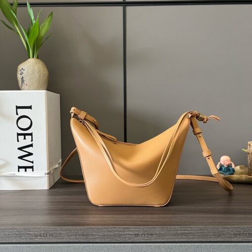 Mini Hammock Hobo. Authentic quality luxury bag crafted in genuine leather comes with authenticity card, dust bag and gift bag. Effortless Form, Everyday Function.  The Mini Hammock Hobo is a contemporary reimagining of Loewe’s iconic Hammock bag. This streamlined variation offers a sleek, sculptural silhouette designed as a versatile sling bag for modern living. Expertly crafted in classic calfskin, it features soft, supple leather and a compact form that adapts effortlessly to your day. The unique design allows for multiple carry options—wear it crossbody, over the shoulder, or by hand. Elegant yet functional, this mini hobo is perfect for essentials, making it an ideal choice for both daily wear and minimalist style statements.