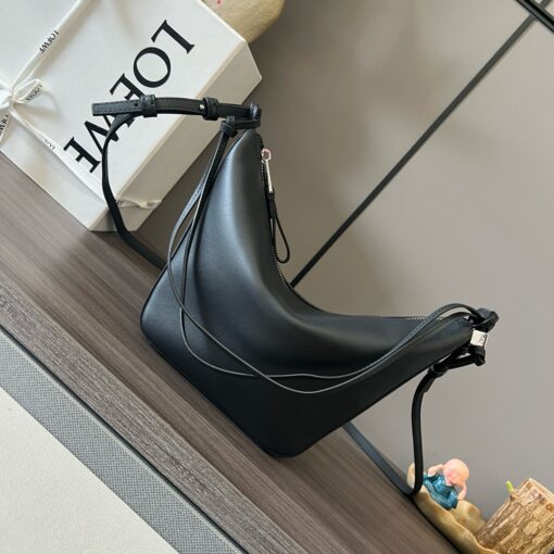 Mini Hammock Hobo. Authentic quality luxury bag crafted in genuine leather comes with authenticity card, dust bag and gift bag. Effortless Form, Everyday Function.  The Mini Hammock Hobo is a contemporary reimagining of Loewe’s iconic Hammock bag. This streamlined variation offers a sleek, sculptural silhouette designed as a versatile sling bag for modern living. Expertly crafted in classic calfskin, it features soft, supple leather and a compact form that adapts effortlessly to your day. The unique design allows for multiple carry options—wear it crossbody, over the shoulder, or by hand. Elegant yet functional, this mini hobo is perfect for essentials, making it an ideal choice for both daily wear and minimalist style statements.