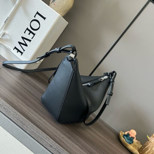 Mini Hammock Hobo. Authentic quality luxury bag crafted in genuine leather comes with authenticity card, dust bag and gift bag. Effortless Form, Everyday Function.  The Mini Hammock Hobo is a contemporary reimagining of Loewe’s iconic Hammock bag. This streamlined variation offers a sleek, sculptural silhouette designed as a versatile sling bag for modern living. Expertly crafted in classic calfskin, it features soft, supple leather and a compact form that adapts effortlessly to your day. The unique design allows for multiple carry options—wear it crossbody, over the shoulder, or by hand. Elegant yet functional, this mini hobo is perfect for essentials, making it an ideal choice for both daily wear and minimalist style statements.