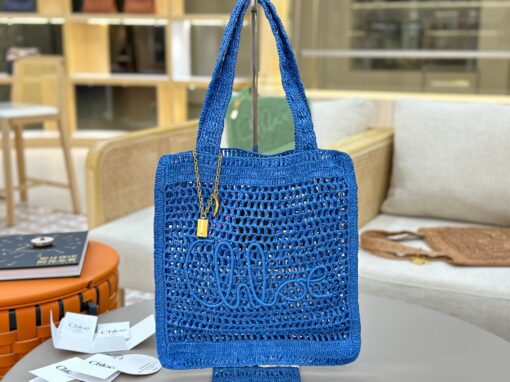 Summer Banana Tote Bag. Authentic quality luxury bag crafted in genuine leather comes with authenticity card, dust bag and gift bag. Heritage in Hand: Where Artisan Craft Meets Summer Elegance. Introducing the Summer Banana Tote—an artisanal masterpiece crafted from raffia and calfskin by a single artisan over 4.5 days in partnership with Made For A Woman. This spacious tote is adorned with a handwritten signature inspired by *loé’s rich heritage, while a playful dangling chain and delicate charms add the perfect finishing touch. A celebration of craftsmanship and effortless summer style.