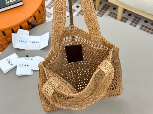 Summer Banana Tote Bag. Authentic quality luxury bag crafted in genuine leather comes with authenticity card, dust bag and gift bag. Heritage in Hand: Where Artisan Craft Meets Summer Elegance. Introducing the Summer Banana Tote—an artisanal masterpiece crafted from raffia and calfskin by a single artisan over 4.5 days in partnership with Made For A Woman. This spacious tote is adorned with a handwritten signature inspired by *loé’s rich heritage, while a playful dangling chain and delicate charms add the perfect finishing touch. A celebration of craftsmanship and effortless summer style.