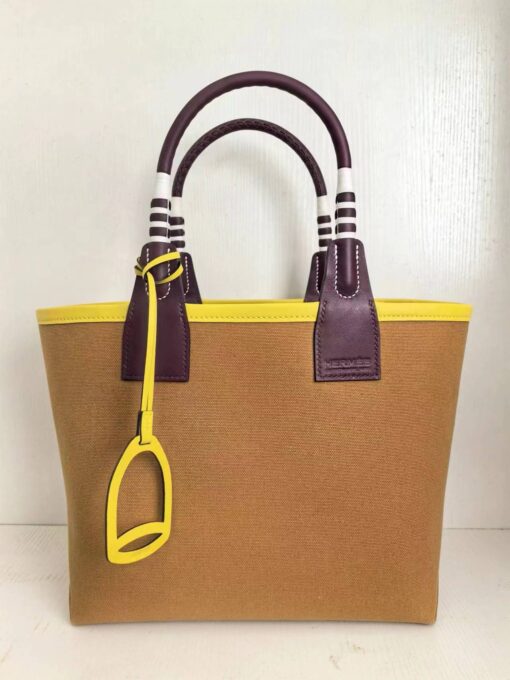 Steeple 25 Bag. Authentic quality luxury bag crafted in genuine leather comes with authenticity card, dust bag and gift bag. Where art meets heritage. The *rmès Steeple Bag is a charming fusion of heritage and artistry, crafted from a blend of canvas and Swift leather. Its design pays tribute to *rmès’ equestrian roots with whip-shaped handles and a stirrup-inspired charm, adding a playful yet sophisticated touch. Lightweight yet spacious, the Steeple is ideal for daily use. Whether you opt for a vibrant motif or a sleek, single-color design, this bag stands out as an artistic expression of luxury that seamlessly integrates into a modern lifestyle. Praised for its unique aesthetic and accessibility within the *rmès lineup, the Steeple Bag is adored by fashion enthusiasts who appreciate its colorful palette and bold personality. While it’s best suited for those who enjoy the texture and look of canvas, it remains a versatile statement piece that captures the spirit of everyday elegance.