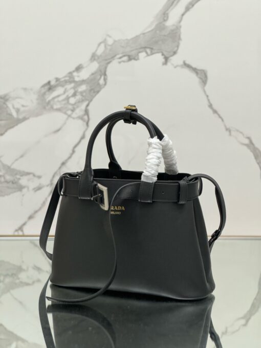 Buckle Small Leather Handbag. Authentic quality luxury bag crafted in genuine leather comes with authenticity card, dust bag and gift bag. Sophistication Meets Utility. Sleek, structured, and undeniably Pr*da — the Buckle Small Leather Handbag captures the brand’s signature balance of minimalist elegance and refined detail. Crafted in smooth leather with a buttery-soft nappa interior, this compact piece is a masterclass in functional luxury. A standout feature? Its interchangeable belt strap, adding a bold, modern twist to the timeless silhouette. Whether you're heading to a meeting or a soirée, this bag adapts seamlessly to your mood and moment. Finished with the embossed iconic logo, it’s a quiet statement of taste and distinction. A versatile companion for the woman who appreciates precision, polish, and just the right touch of edge.