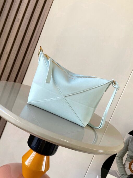 Puzzle Fold Pouch. Authentic quality luxury bag crafted in genuine leather comes with authenticity card, dust bag and gift bag. Sculpted Sophistication — The Art of Function. The Puzzle Fold Pouch redefines modern elegance with its sculptural geometry and effortless versatility. Crafted in luxurious shiny nappa calfskin, its signature folded panels create a dynamic, architectural silhouette that’s instantly recognizable. Both stylish and practical, this pouch transitions seamlessly from day to night—perfect for carrying essentials with a touch of *OEWE sophistication. A masterpiece of craftsmanship, it’s the ultimate blend of innovation and timeless design.
